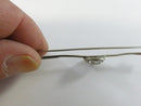 Side view of riding crop bar pin showing its slightly wavy bar and raised cabochon
