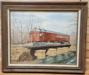 Framed painting of a red train car on a stone bridge over water, displayed on a wooden wall.