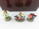 Three Department 56 Disney Parks Family porcelain figurine accessories displayed in front of the burgundy Heritage Village Collection box.