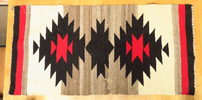 This authentic Navajo area rug is a testament to the enduring craftsmanship of the Southwest. The intricate geometric design, woven with care using natural dyes, tells a story of generations of Navajo weavers. Although showing signs of wear, the rug's patina adds to its character and charm.