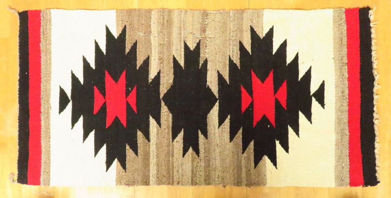 This authentic Navajo area rug is a testament to the enduring craftsmanship of the Southwest. The intricate geometric design, woven with care using natural dyes, tells a story of generations of Navajo weavers. Although showing signs of wear, the rug's patina adds to its character and charm.