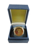 Gold ring with intricate design in a blue box on a white background