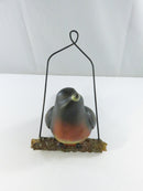 Left-side view of the robin bird figurine showing its tail, wing, faux bark perch, and metal wire hanger