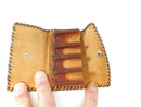 Open tan leather wallet showing snap closure and brown four-slot plastic coin dispenser