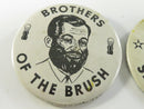 Metal backs of two pinback buttons with embedded wire clasp fasteners and visible oxidation.