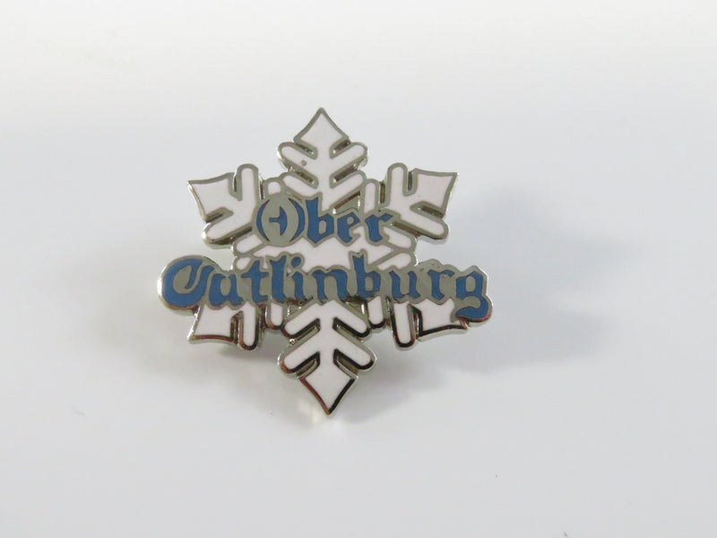 Metallic snowflake-shaped pin with 'Ober Gatlinburg' text on a white background