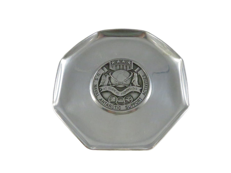 Silver octagonal object with a central emblem on a white background