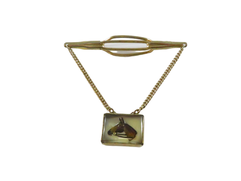 Gold tie clip with a square pendant featuring a horse's head on a white background