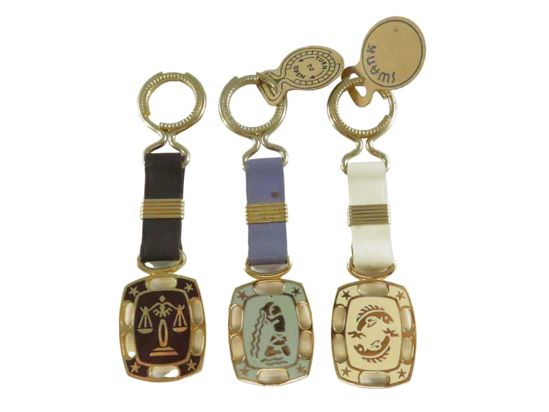 Three decorative keychains with zodiac symbols on a white background