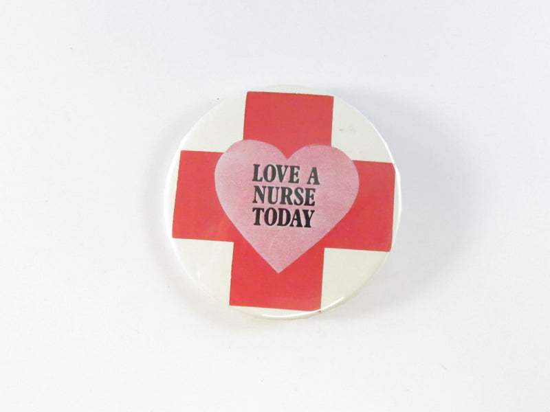 Button badge with red cross and heart design, text 'Love a Nurse Today' on a white background