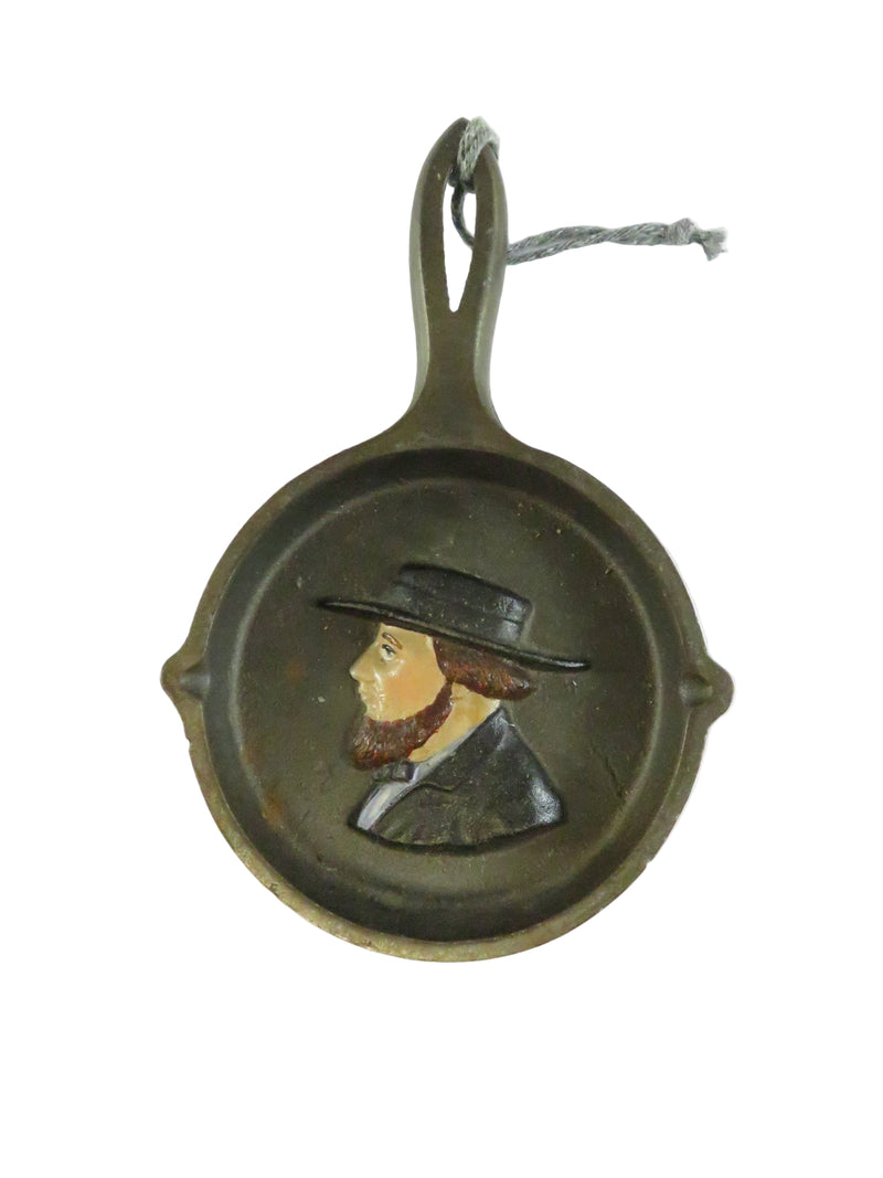 Small cast iron skillet with a decorative handle on a white background