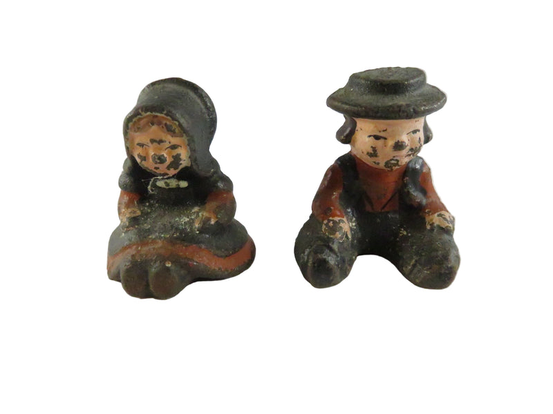 Two vintage cast iron figures of a man and a woman on a white background