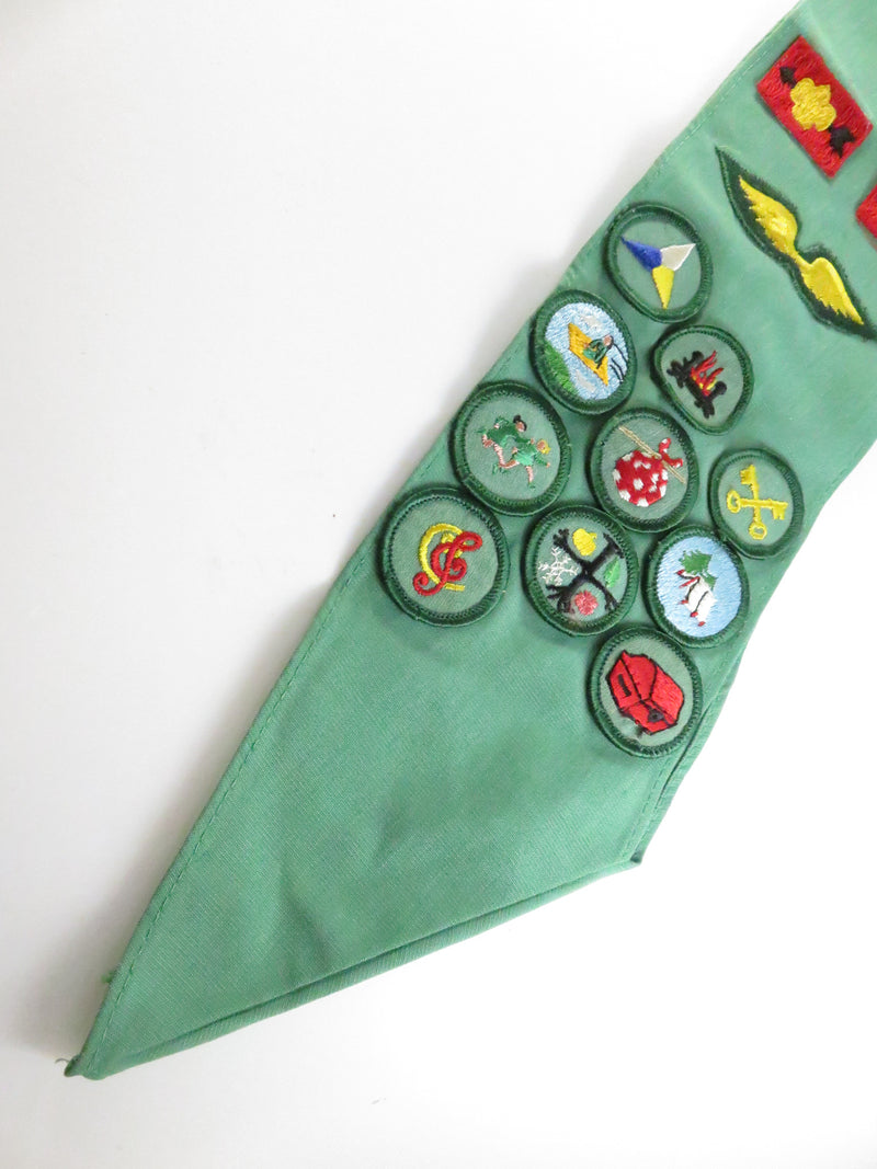 Green neckerchief with various embroidered badges on a white background