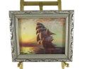Framed painting of a ship at sunset on an easel