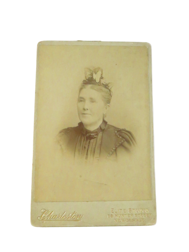 Vintage sepia-toned portrait of a woman with a decorative hairpiece, framed by a yellow border.