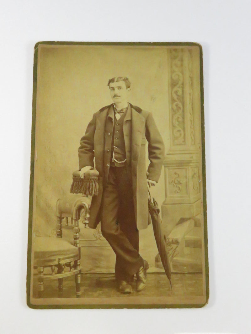 Vintage sepia-toned photograph of a man holding a sword on a decorative background