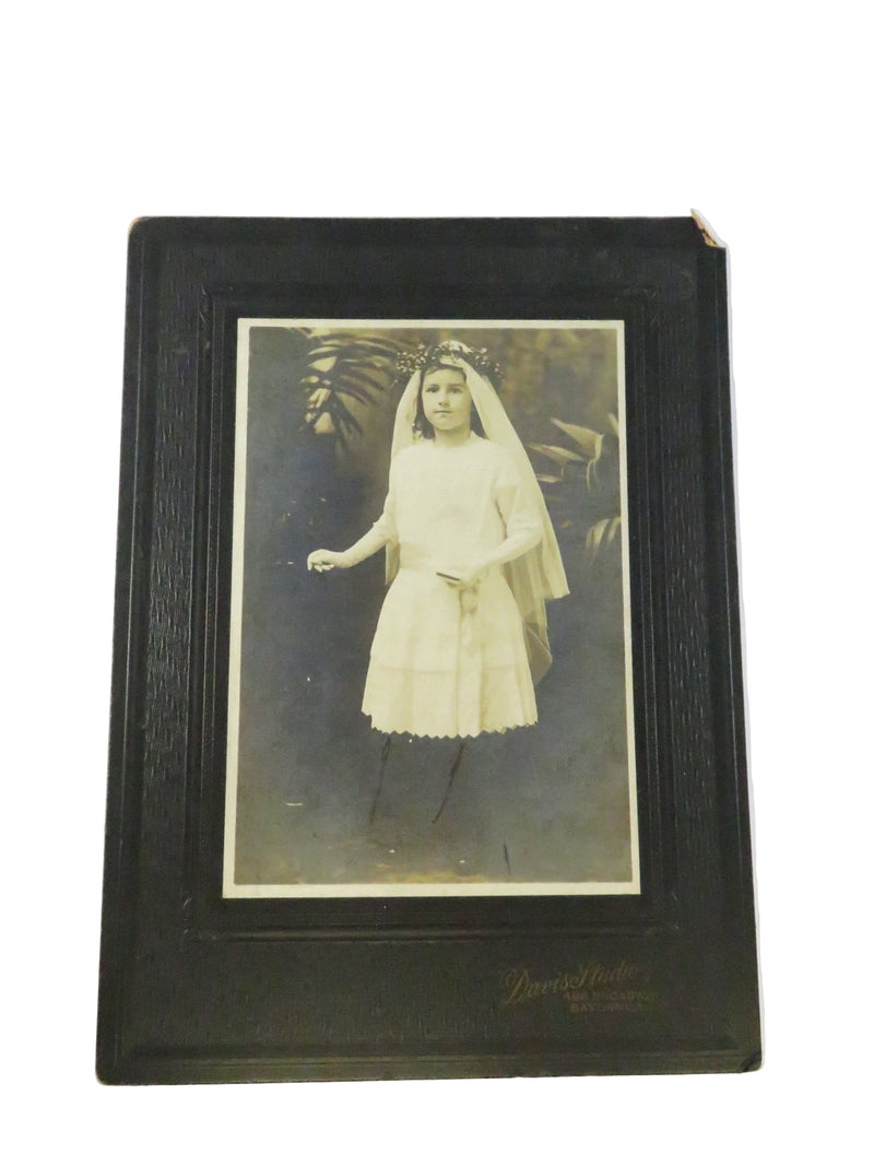 Vintage photo album with a black border containing an old photograph of a person in formal attire.