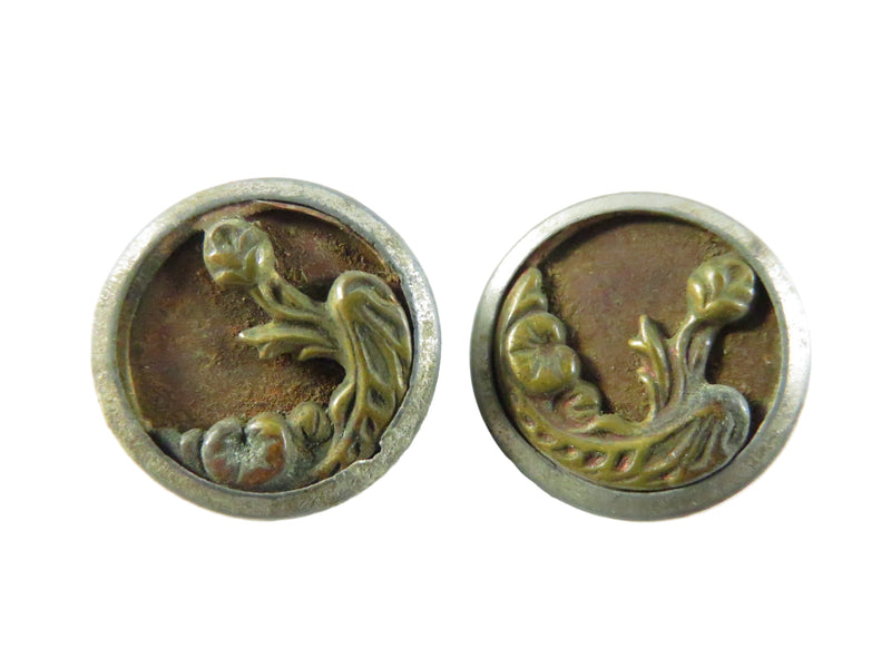 Pair of round metal buttons with floral design on a white background