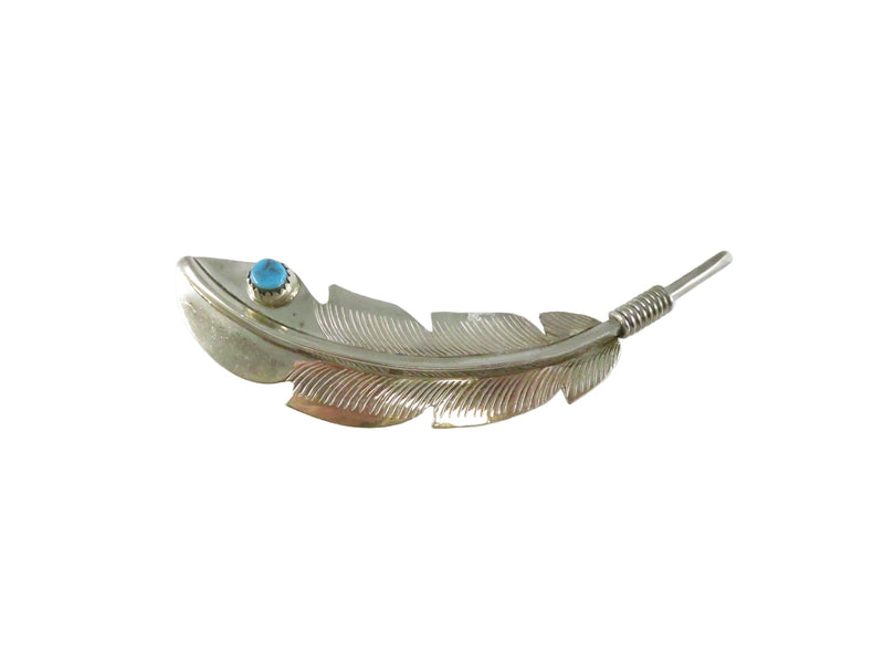 Silver feather-shaped brooch with a blue gemstone on a white background