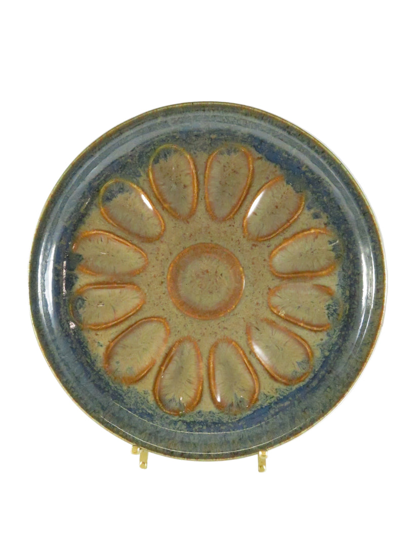 Pottery egg plate with glazed flower design on a white background