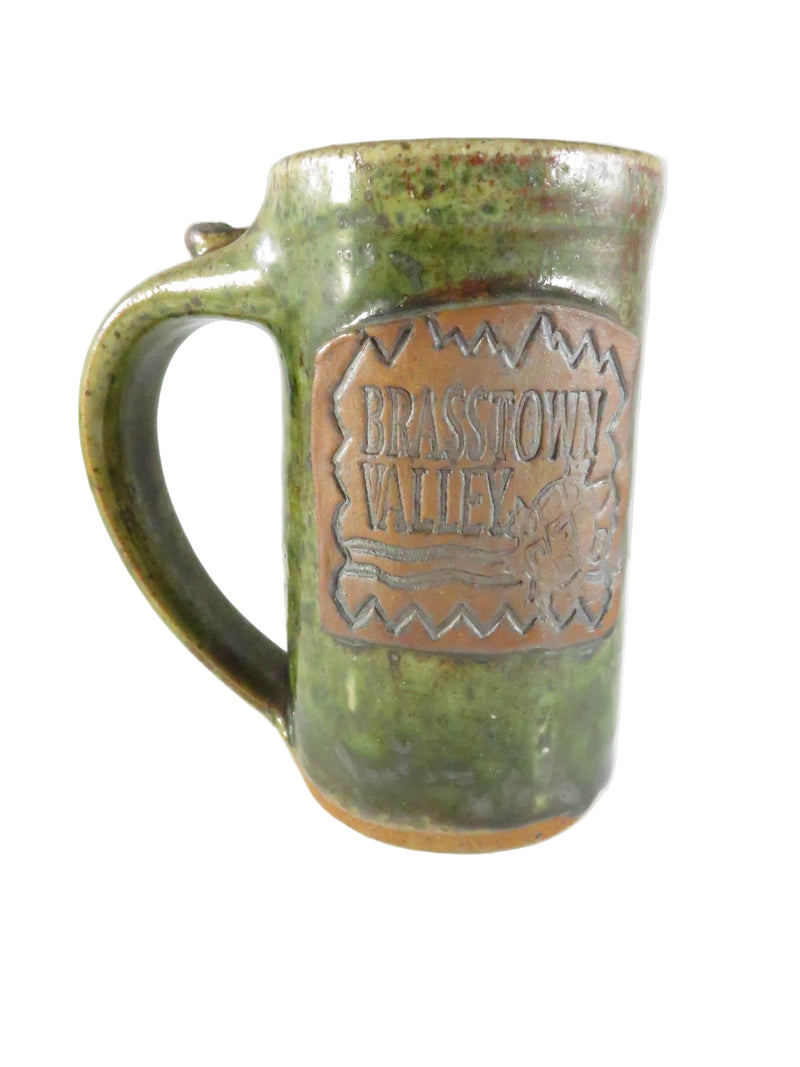 Green ceramic mug with a copper-colored logo on a white background