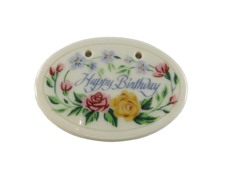Oval-shaped ceramic ornament with floral design and 'Happy Birthday' text on a white background
