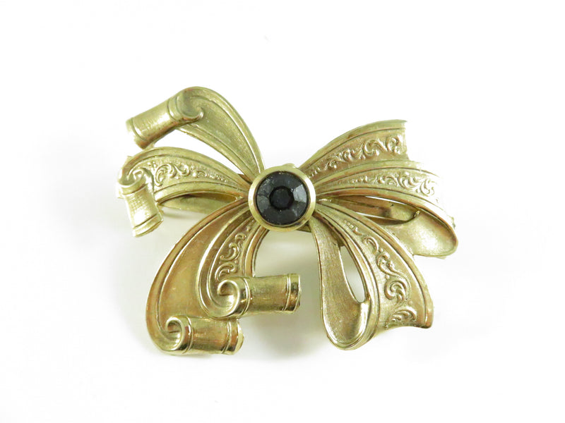 Gold brooch with black gemstone on a white background