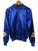 Blue jacket with a logo on a wooden hanger against a wooden wall.