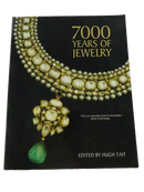 Front cover of 7000 Years of Jewelry, edited by Hugh Tait, with a jeweled gold necklace and green pendant on a black background.