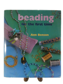 Front dust jacket of Beading for the First Time by Ann Benson, with beadwork materials and jewelry projects pictured.