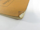Close view of the lower front-cover corner showing creasing, wear, and chipped paper edges.