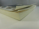 Low side view of the paperback showing the curled front cover, page block, and worn edges.