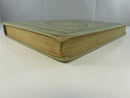 Low angled view of the book's spine and fore-edge, showing the gilt spine title and worn cloth at the spine ends.