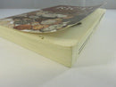 Angled view of the paperback's lower page block and curled front cover edge, showing tanning and wear.