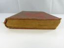 Low side view of the book showing a heavily worn page block, frayed spine end, and bowed covers.