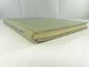Low view of the lower spine, fore-edge, and front cover of the green cloth hardcover, showing wear at the spine foot.