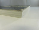 Low side view of the paperback showing the page block, curled cover edge, and visible cover chipping.