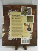 Back cover of Enchanted Adornments showing the Interweave logo, mixed-media jewelry photographs, description text, and ISBN 978-1-59668-157-6.