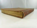 Angled view of the upper edge, spine, and worn cloth boards.