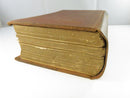 Side view of stacked brown cloth volumes showing worn page edges, splayed boards, and weakened structure.