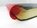 Close side view of the red plastic comb binding and toned page edges at one end of the text block.