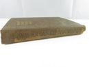 Low side view of the worn cloth spine, showing faded stamped title lettering and fraying at the tail.