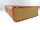 Bottom page edges and worn gilt-decorated spine of the other volume, with frayed cloth at the joints.
