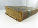 Angled view of the worn spine, board edges, and aged text block.