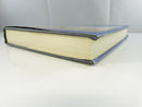 Open front cover with dust-jacket flap, blank endpaper, and handwritten notation inside the front cover.