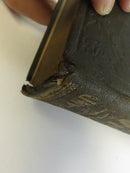 Close view of the damaged lower spine and board corner with broken cloth and exposed structure.