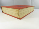 Bottom and fore-edge view of the aged text block and worn red cloth board edges.