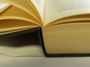 Close-up of the book’s open pages, text block, and black hardcover board at the hinge.