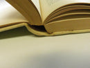 Open hardcover showing the inner hinge, text block, and age-toned pages