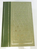 Full view of a green textured hardcover board with gilt border, diamond pattern, and floral motifs.